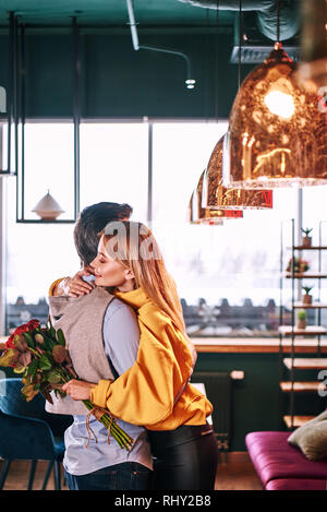 Profiter bon week-end ensemble. L'homme est serrant sa petite amie avec passion. Jeune blonde woman is holding buquet avec roses rouges Banque D'Images