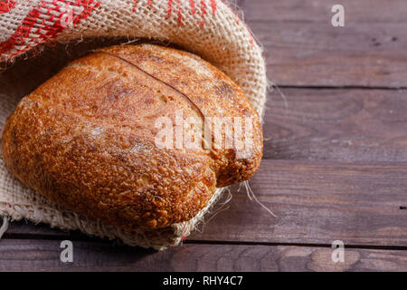 Du pain artisanal traditionnel en jute sur fond de bois. Close-up. Banque D'Images