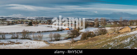 Paysage de Teesdale, vue panoramique sur le village rural de Hutton Magna à Barningham Moor avec champs couverts de neige, soleil et ciel sombre Banque D'Images