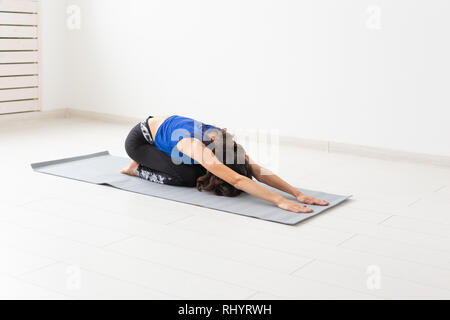 Mode de vie sain, et le sport concept - Jeune femme avec des cheveux bouclés faisant du yoga sur fond blanc Banque D'Images