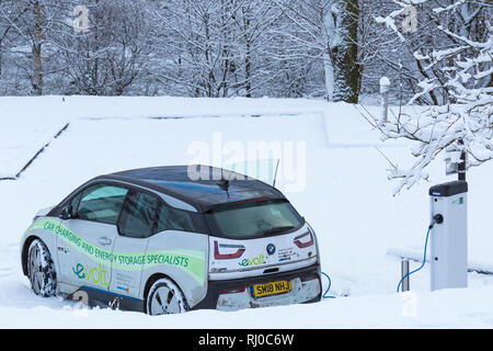 Voiture électrique BMW étant facturé à la station de recharge pour voitures électriques dans la neige point couvert par Clachaig Inn, Glencoe, Highlands, Scotland en hiver Banque D'Images