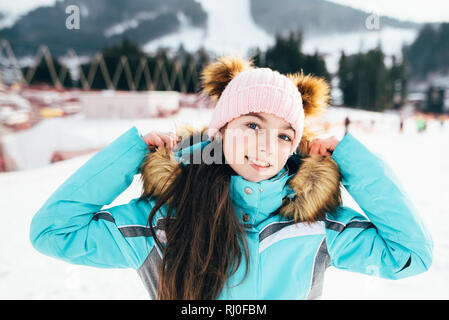 Belle fille dans une veste de ski promenades sur un jour de printemps ensoleillé dans les montagnes. Banque D'Images