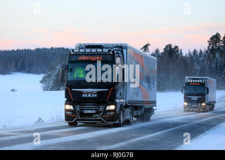 Salo, Finlande - le 18 janvier 2019 : Deux camions semi-remorque homme personnalisé de Stengel LT transporter les marchandises à travers un paysage d'hiver au crépuscule dans le sud de la Finlande. Banque D'Images