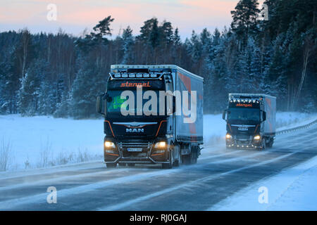 Salo, Finlande - le 18 janvier 2019 : Deux camions semi-remorque homme personnalisé de Stengel LT transporter les marchandises à travers un paysage d'hiver au crépuscule dans le sud de la Finlande. Banque D'Images