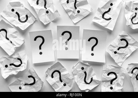 Trois points d'interrogation sur les cartes blanche entourée d'un cadre de feuilles de papier froissé imprimé également avec des points d'interrogation dans un contexte conc Banque D'Images