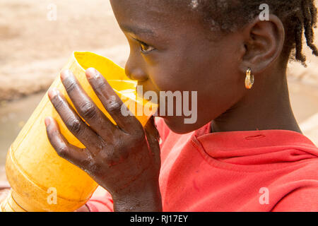 La-toden village, province de Yako, Burkina Faso. Les femmes du petit jardin à proximité de leur domicile. Le puits ici sont plus profonds et n'exécutez pas sèche. Les enfants prennent un verre d'eau de puits dans le milieu de journée. Banque D'Images