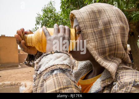 La-toden village, province de Yako, Burkina Faso. Les femmes du petit jardin à proximité de leur domicile. Le puits ici sont plus profonds et n'exécutez pas sèche. Les enfants prennent un verre d'eau de puits dans le milieu de journée. Banque D'Images