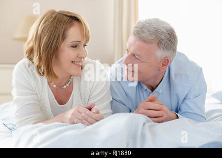 Smiling mature woman alors que lying on bed Banque D'Images