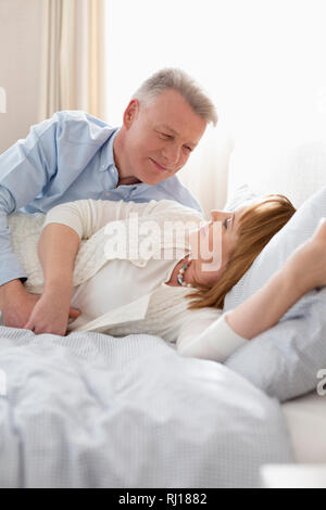 Mature couple lying on bed at home Banque D'Images