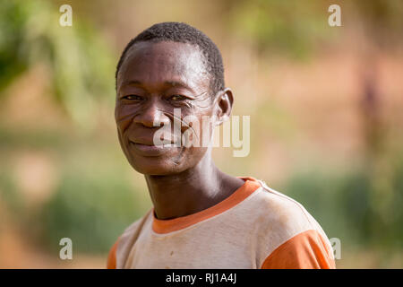 Village de samba, Province de Yako, Burkina Faso : le portrait de Denis Zoundi, 45,avec les cicatrices, tandis que l'arrosage des cultures sur son market garden. Banque D'Images