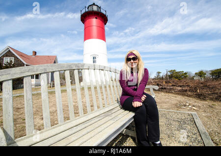 Portrait d'une belle femme blonde assise sur un banc en face de Nauset Lighthouse à Cape Cod Banque D'Images