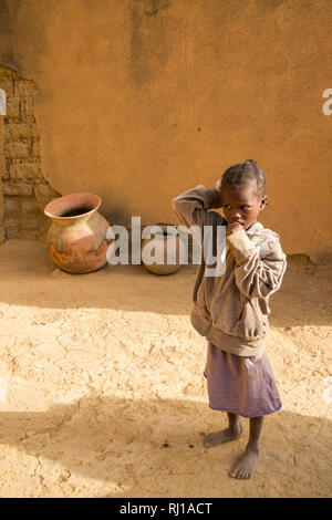 Village de samba, Province de Yako, Burkina Faso : Une jeune fille, montres pendant que sa mère parler aux autres villageois. Banque D'Images