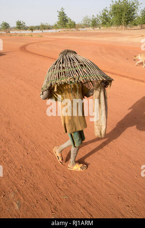 Village de samba, Province de Yako, Burkina Faso : Un jeune garçon carryng un panier de pêche pour pêcher dans le lac sur l'un des jours où la pêche est autorisée. Banque D'Images
