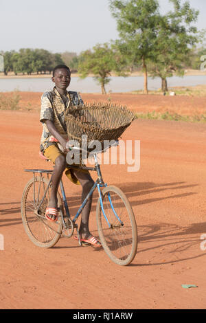 Village de samba, Province de Yako, Burkina Faso : un jeune pêcheur sur son chemin avec son baket de pêche pour pêcher dans le lac sur l'un des jours où la pêche est autorisée. Banque D'Images