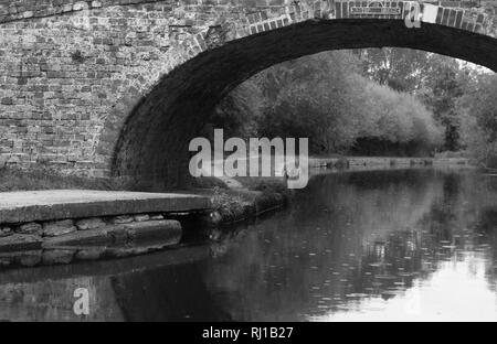 Pont en arc au-dessus de l'eau en noir et blanc Banque D'Images