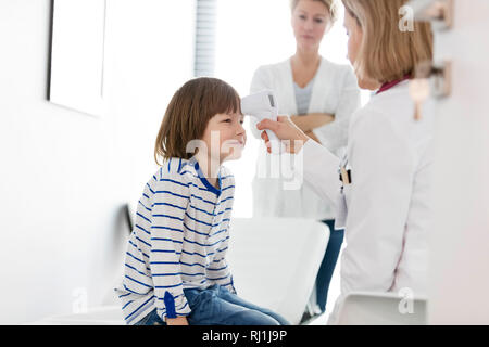 Mesure de la température du jeune médecin avec un thermomètre à infrarouge à l'hôpital Banque D'Images