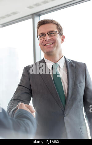 Smiling businessman shaking hands with colleague in office Banque D'Images