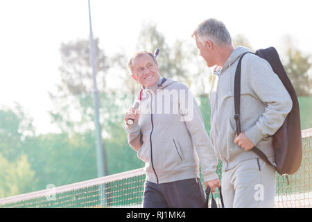 Smiling men dans les vêtements de sport à parler tout en marchant sur un court de tennis Banque D'Images