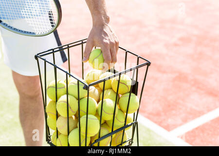 Portrait de l'homme prise de balle de tennis panier métallique sur sunny day Banque D'Images