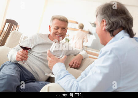 Smiling mature hommes parler alors qu'il était assis dans la salle de séjour à la maison Banque D'Images