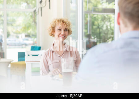 Smiling woman looking at man sitting in restaurant Banque D'Images