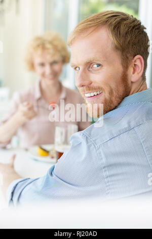 Portrait of smiling man sitting with woman in restaurant Banque D'Images