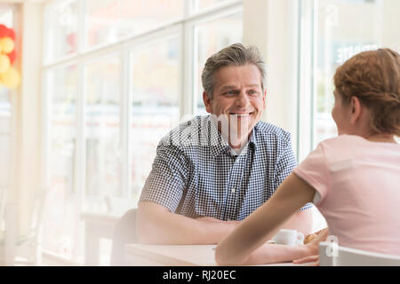 Smiling young man sitting with young woman at table in restaurant Banque D'Images