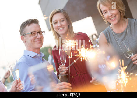 Smiling holding wineglasses cierges et collègues au cours de partie sur le toit Banque D'Images