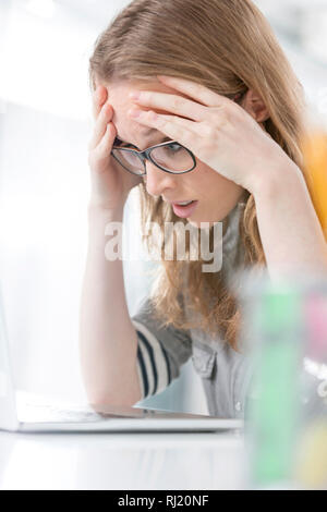 Souffrant de maux de tête surchargés de businesswoman in office Banque D'Images