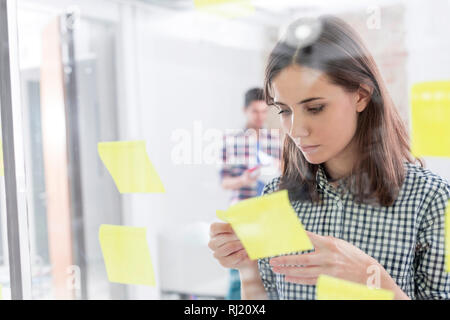 Young businesswoman reading des rappels dans office Banque D'Images