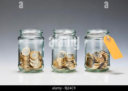Trois pots en verre Enregistrer avec pièces Livre Banque D'Images