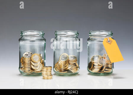 Trois pots en verre Enregistrer avec pièces Livre Banque D'Images