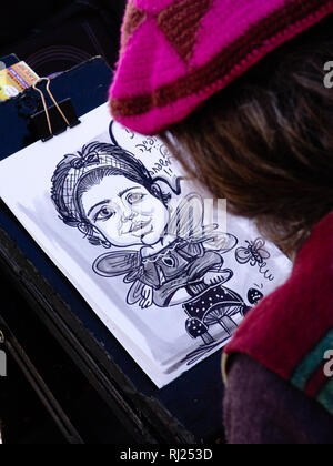 Artiste avec purple hat, dans le processus de création d'une illustration de dessin d'une jeune fille sur papier blanc, dans un cadre urbain. Banque D'Images