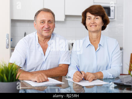 Portrait of mature couple positif au remplissage des documents table de cuisine Banque D'Images