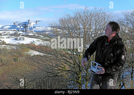 Un homme aux commandes d'un drone dans un paysage de neige hiver rural dans la campagne du Carmarthenshire Wales UK KATHY DEWITT Banque D'Images