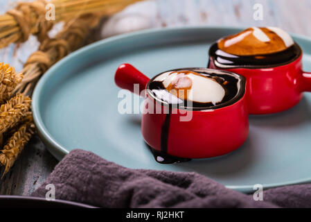 Blanc crème fouettée dans deux jolies petites tasses rouge avec poignée Banque D'Images