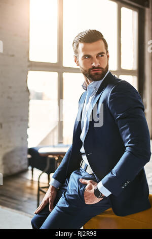 Photo de l'intérieur jeune patron européen en costume élégant au bureau permanent moderne amd à la route. Concept d'entreprise. Fashion look. Banque D'Images