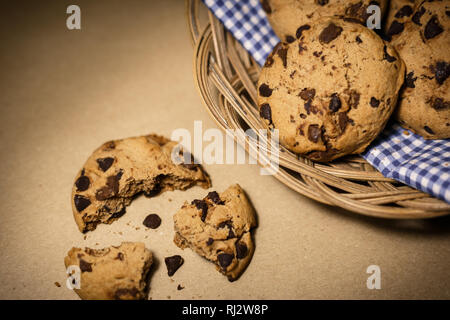 Copeaux de chocolat cookies dans un panier en bois . La photographie alimentaire thème en vintage ou rétro style de couleur. Banque D'Images