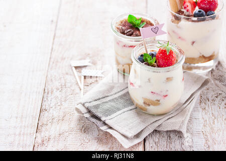 Tiramisu dessert italien fait maison avec des fraises, de menthe et de cacao dans des bocaux en verre, gros plan Banque D'Images