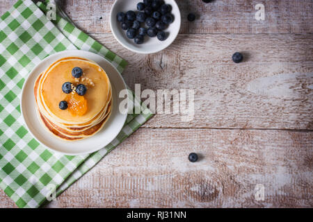 Sweet pancakes faits maison avec des bleuets, des fruits de la confiture et du miel sur une plaque blanche Banque D'Images