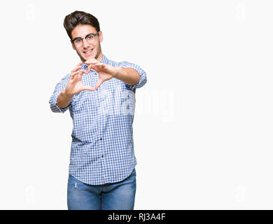 Beau jeune homme portant des lunettes au fond isolé smiling in love montrant le symbole de coeur et la forme des mains. Concept romantique. Banque D'Images