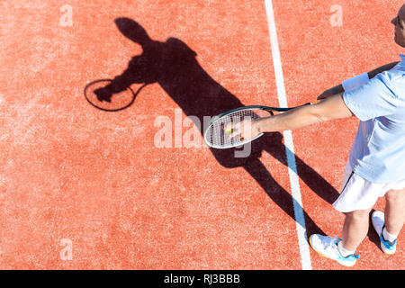 High angle view of mature man servant balle de tennis sur cour rouge Banque D'Images