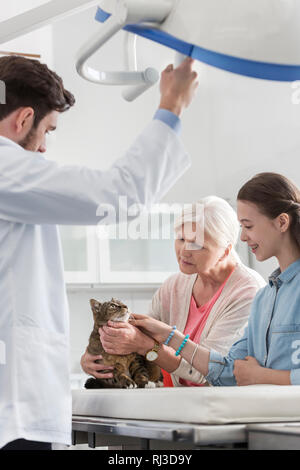 Doctor standing with woman and girl looking at chat dans une clinique vétérinaire Banque D'Images