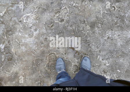 Personne pieds de bottes debout sur la neige sale slush en fin de l'hiver. Météo dégel, printemps prochains. Service de protection saisonnière avec des Banque D'Images