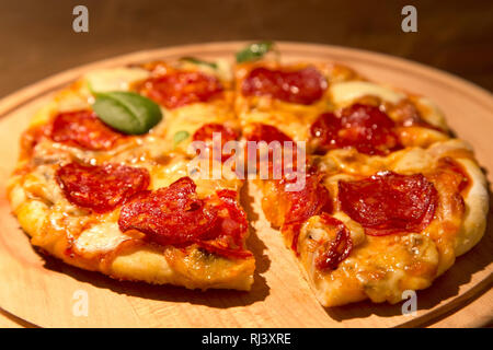 Pizza au pepperoni, sur une plaque de bois Banque D'Images