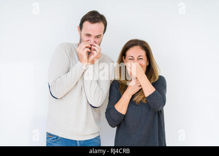 Beau couple d'âge moyen de l'amour sur fond isolé humer un stinky et dégoûtant, odeur insupportable, apnée avec les doigts Banque D'Images