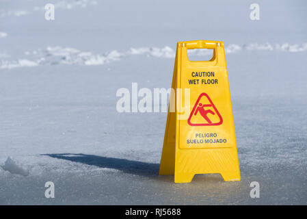 Un panneau jaune carte attention plancher mouillé sur un lac gelé. Selective focus Banque D'Images