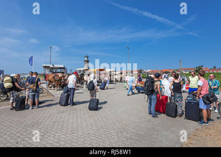 Urlauber, Pferdekutschen, Ankunft am Hafen, im Hintergrund Leuchtturm Memmertfeuer auf der Insel Juist, Ostfriesische Insel, Banque D'Images