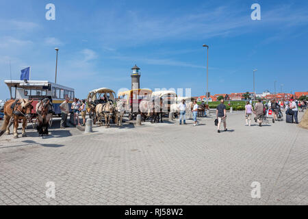 Urlauber, Pferdekutschen, Ankunft am Hafen, im Hintergrund Leuchtturm Memmertfeuer auf der Insel Juist, Ostfriesische Insel, Banque D'Images