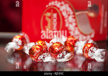 Chocolats Lindt Lindor pralines bonbons enveloppés, en pack, dessert sucré sur fond rouge, en personne, Banque D'Images